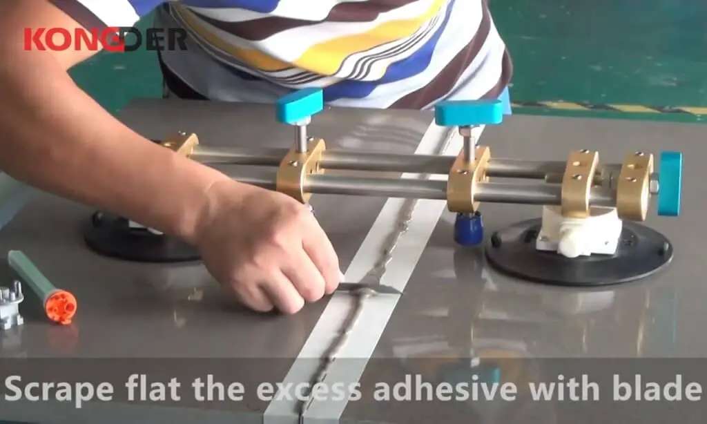 Scrape flat the excess adhesive with blade